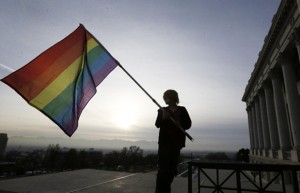 A man holds a rainbow flag in front of the capitol building in Utah