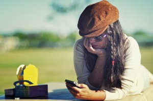 A woman looks at her phone with a bucolic landscape in the background