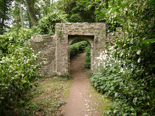 Image of a stone wall in a garden with a passage through it