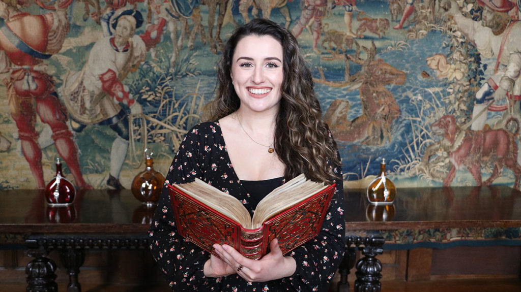 woman with long hair holding a prayer book with golden-edge pages