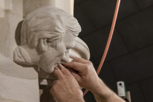 hands adjusting a sculpture of Elie Weisel in a cathedral doorway